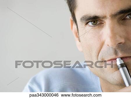 Man with pen in front of lips, close-up View Large Photo Image Stock Photograph - Man with pen in front of lips, close-up. Fotosearch