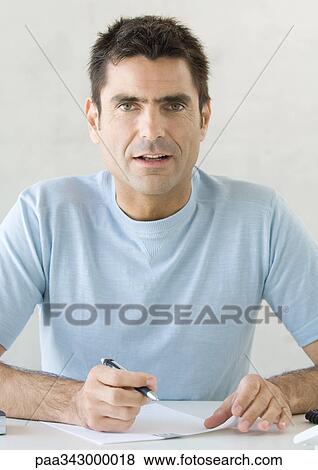 Man writing, looking at camera View Large Photo Image Stock Photo - Man writing, looking at camera. Fotosearch