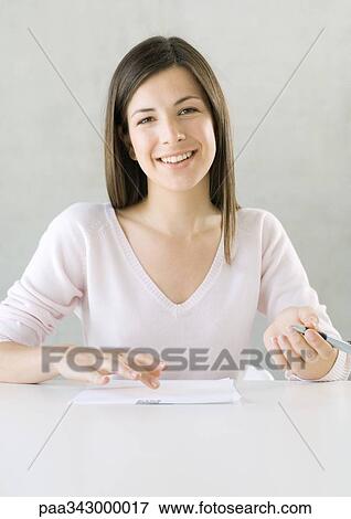 Woman with paper and pen, smiling at camera View Large Photo Image Stock Photo - Woman with paper and pen, smiling at camera. Fotosearch