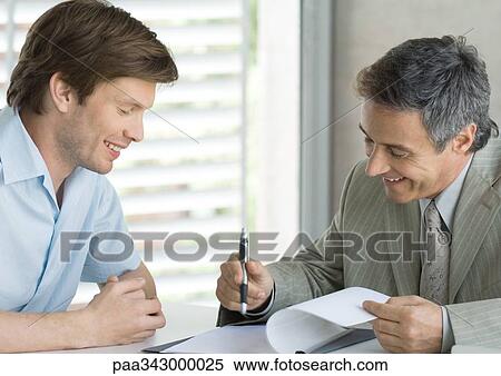 Young man with mature business man, looking at document View Large Photo Image Stock Photography - Young man with mature business man, looking at document. Fotosearch