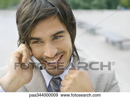 Businessman using cell phone, smiling, and clenching fist View Large Photo Image Stock Photo - Businessman using cell phone, smiling, and clenching fist. Fotosearch