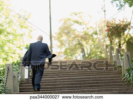 Stock Photo - Businessman walking up stairs, rear view. Fotosearch