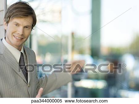 Young businessman smiling at camera and gesturing View Large Photo Image Stock Photography - Young businessman smiling at camera and gesturing. Fotosearch