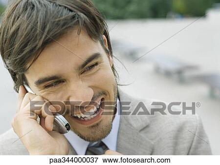 Young businessman using cell phone and laughing View Large Photo Image Stock Photo - Young businessman using cell phone and laughing. Fotosearch