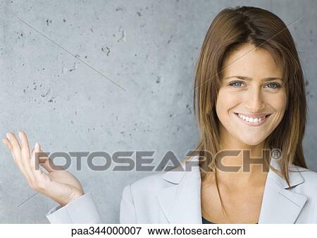 Stock Photo - Young businesswoman smiling and holding up hand, portrait. Fotosearch