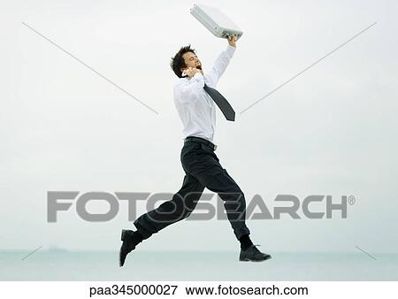 Businessman running and jumping, with cell phone and briefcase View Large Photo Image Stock Photo - Businessman running and jumping, with cell phone and briefcase. Fotosearch