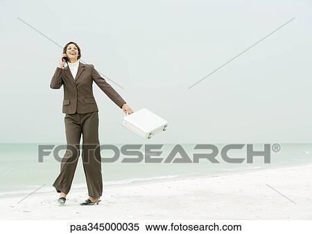 Businesswoman using cell phone and swinging briefcase on beach View Large Photo Image Stock Photography - Businesswoman using cell phone and swinging briefcase on beach. Fotosearch
