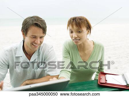 Man and woman, using laptop on beach View Large Photo Image Stock Image - Man and woman, using laptop on beach. Fotosearch
