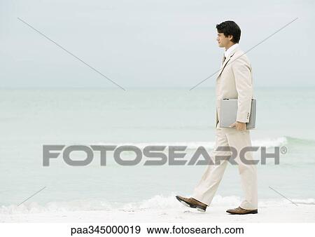 Man carrying laptop under arm, on beach View Large Photo Image Stock Photo - Man carrying laptop under arm, on beach. Fotosearch