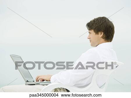 Picture - Man using laptop outdoors. Fotosearch