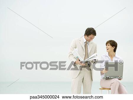 Two business people on beach, one using laptop, the other reading newspaper View Large Photo Image Picture - Two business people on beach, one using laptop, the other reading newspaper. Fotosearch