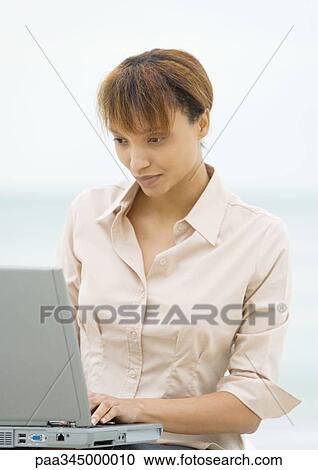 Stock Image - Woman using laptop outdoors. Fotosearch