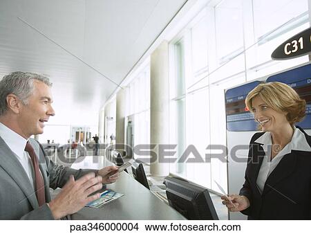 Picture - Businessman at airline check-in counter. Fotosearch