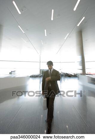 Businessman checking watch in concourse, blurred motion View Large Photo Image Picture - Businessman checking watch in concourse, blurred motion. Fotosearch