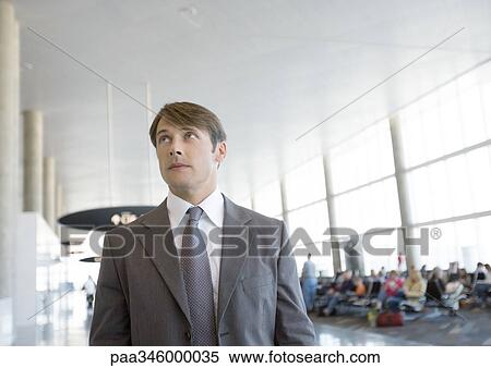 Stock Photography - Businessman in airport, looking up. Fotosearch