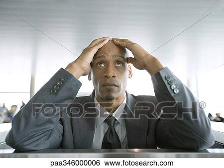 Businessman looking up and holding head in airport View Large Photo Image Stock Photograph - Businessman looking up and holding head in airport. Fotosearch
