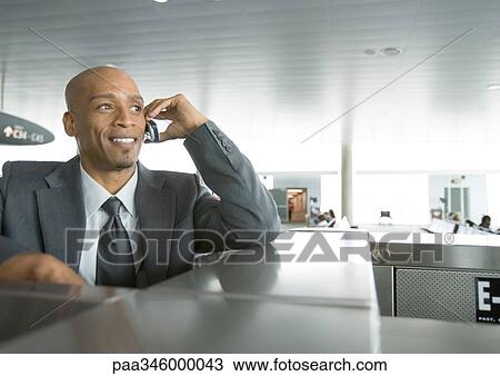 Businessman using cell phone in airport View Large Photo Image Stock Image - Businessman using cell phone in airport. Fotosearch