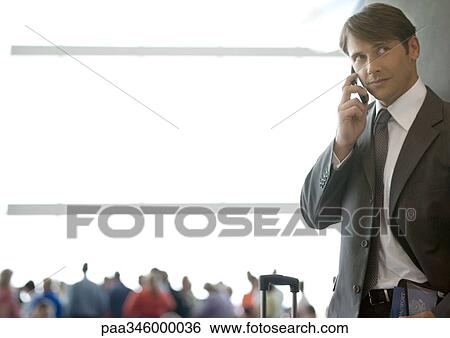 Businessman using cell phone in airport View Large Photo Image Stock Photograph - Businessman using cell phone in airport. Fotosearch