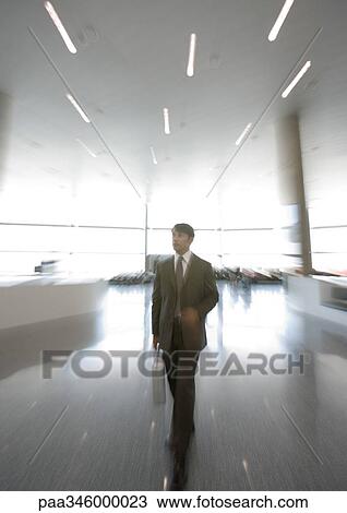 Businessman walking through concourse, blurred motion View Large Photo Image Stock Image - Businessman walking through concourse, blurred motion. Fotosearch