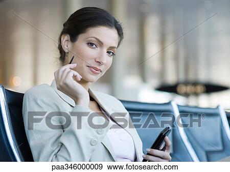 Businesswoman using electronic organizer in airport lounge, smiling at camera View Large Photo Image Stock Photo - Businesswoman using electronic organizer in airport lounge, smiling at camera. Fotosearch