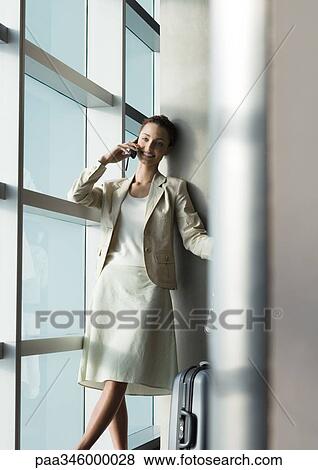 Stock Photo - Female traveler using cell phone by window. Fotosearch