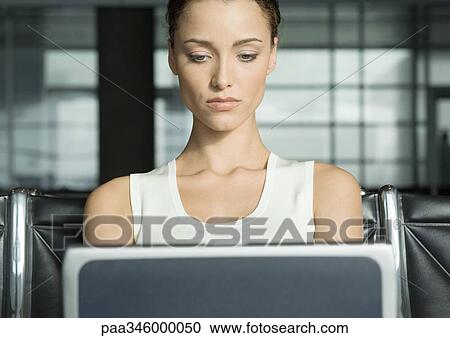 Female traveler using laptop in airport lounge View Large Photo Image Stock Image - Female traveler using laptop in airport lounge. Fotosearch