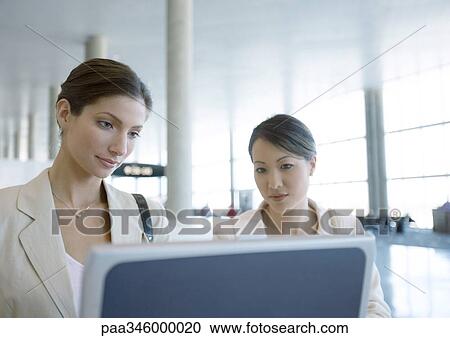 Two women looking at screen in airport View Large Photo Image Stock Image - Two women looking at screen in airport. Fotosearch
