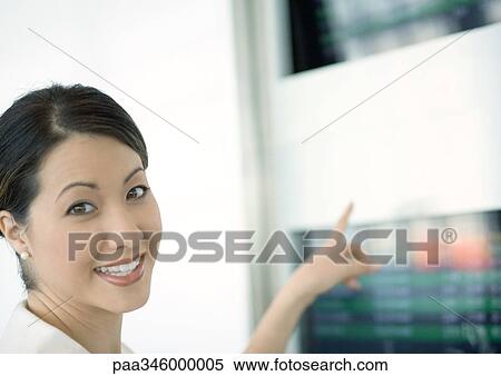 Stock Photography - Woman pointing to departure board. Fotosearch