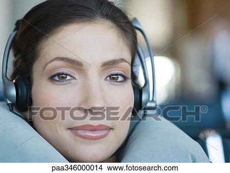 Woman wearing headphones and using neck pillow, close-up View Large Photo Image Picture - Woman wearing headphones and using neck pillow, close-up. Fotosearch