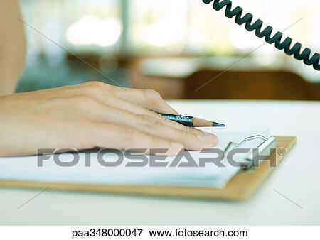 Person using phone, holding pencil with hand on clipboard, extreme close-up View Large Photo Image Stock Photo - Person using phone, holding pencil with hand on clipboard, extreme close-up. Fotosearch