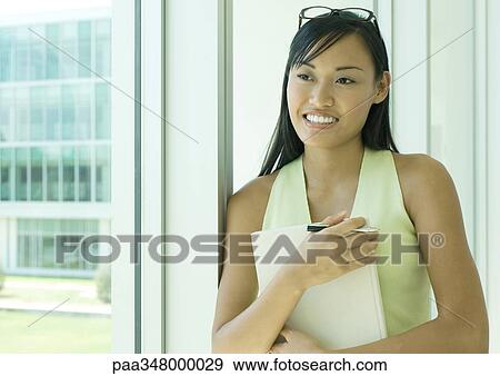 Stock Photo - Woman holding agenda, smiling. Fotosearch