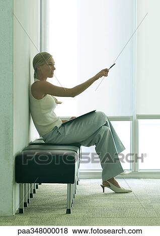 Stock Photo - Woman sitting in office lobby, pointing. Fotosearch