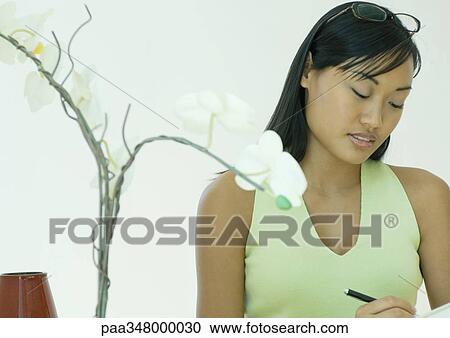 Woman writing, orchid in foreground View Large Photo Image Stock Image - Woman writing, orchid in foreground. Fotosearch