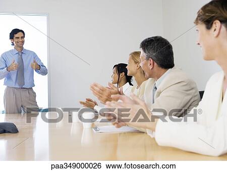 Business meeting, man standing with thumbs up while colleagues clap View Large Photo Image Stock Photograph - Business meeting, man standing with thumbs up while colleagues clap. Fotosearch