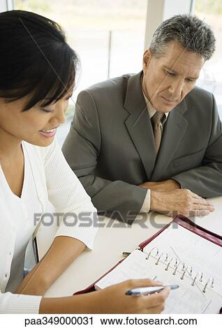 Businessman and assistant looking at agenda together View Large Photo Image Stock Image - Businessman and assistant looking at agenda together. Fotosearch