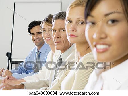 Picture - Group of executives sitting in row, looking at camera. Fotosearch