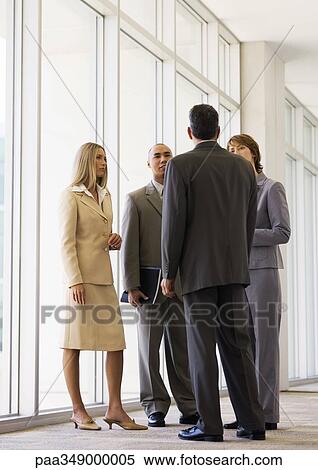 Group of executives standing in corridor having discussion View Large Photo Image Stock Photography - Group of executives standing in corridor having discussion. Fotosearch