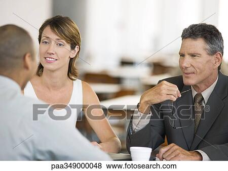 Stock Photo - Three business colleagues having conversation. Fotosearch