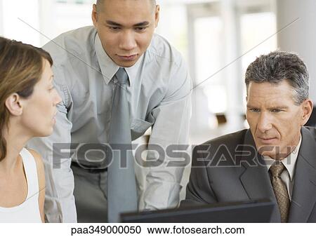 Three young executives working together around laptop View Large Photo Image Stock Image - Three young executives working together around laptop. Fotosearch