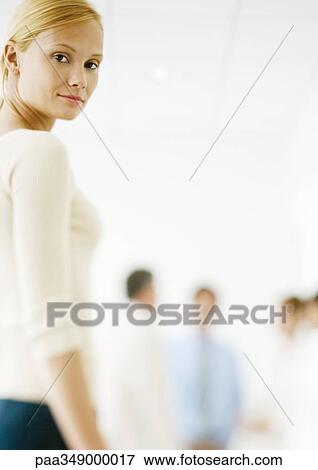 Stock Photo - Young professional woman, standing looking over shoulder at camera. Fotosearch