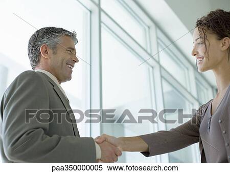 Stock Photography - Businessman shaking hands with woman. Fotosearch