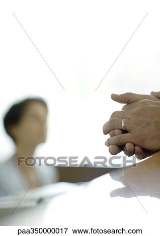 Man's clasped hands on reception desk, receptionist in background View Large Photo Image Stock Photo - Man's clasped hands on reception desk, receptionist in background. Fotosearch