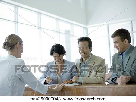 Stock Image - People standing at reception desk, laughing. Fotosearch