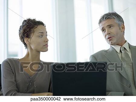 Two business colleagues having discussion and using laptop View Large Photo Image Stock Image - Two business colleagues having discussion and using laptop. Fotosearch