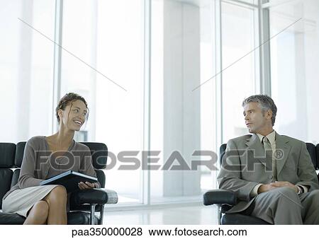 Two business professionals chatting in office lobby View Large Photo Image Stock Photo - Two business professionals chatting in office lobby. Fotosearch