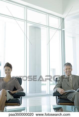Two business professionals sitting in office lobby, smiling at camera View Large Photo Image Stock Image - Two business professionals sitting in office lobby, smiling at camera. Fotosearch