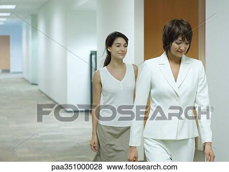 Stock Photo - Businesswoman and assistant walking through corridor. Fotosearch