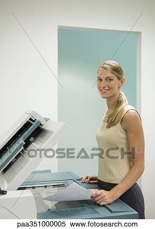 Female office worker standing at copy machine, smiling at camera View Large Photo Image Stock Photography - Female office worker standing at copy machine, smiling at camera. Fotosearch