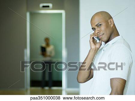 Stock Photo - Man phoning, elevator in background. Fotosearch