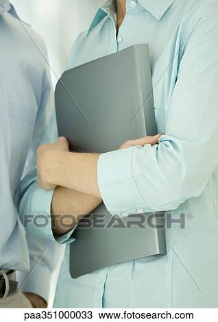 Office worker holding file against chest View Large Photo Image Stock Image - Office worker holding file against chest. Fotosearch
